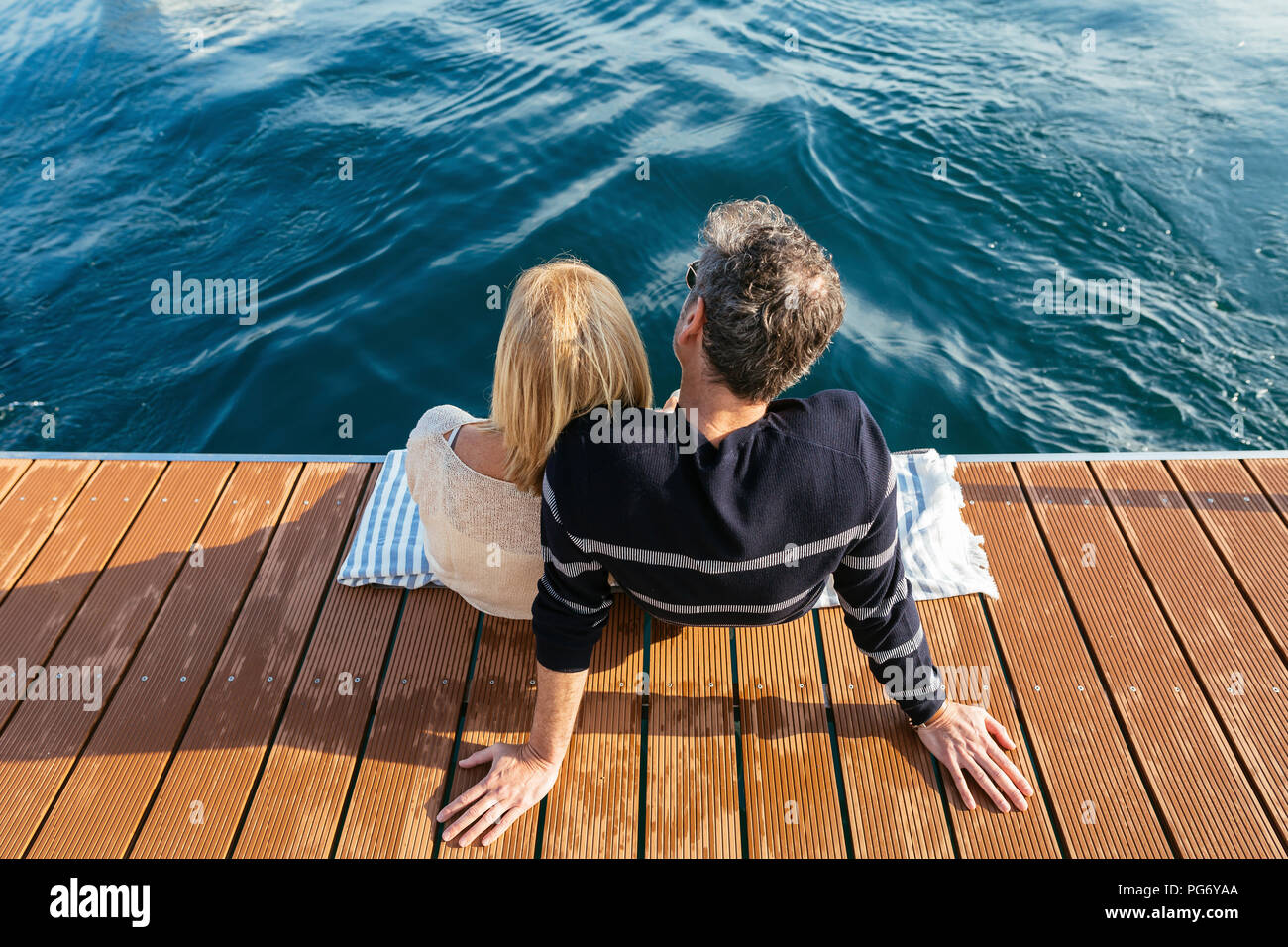 Mature couple sitting on jetty, relaxing at the sea Stock Photo