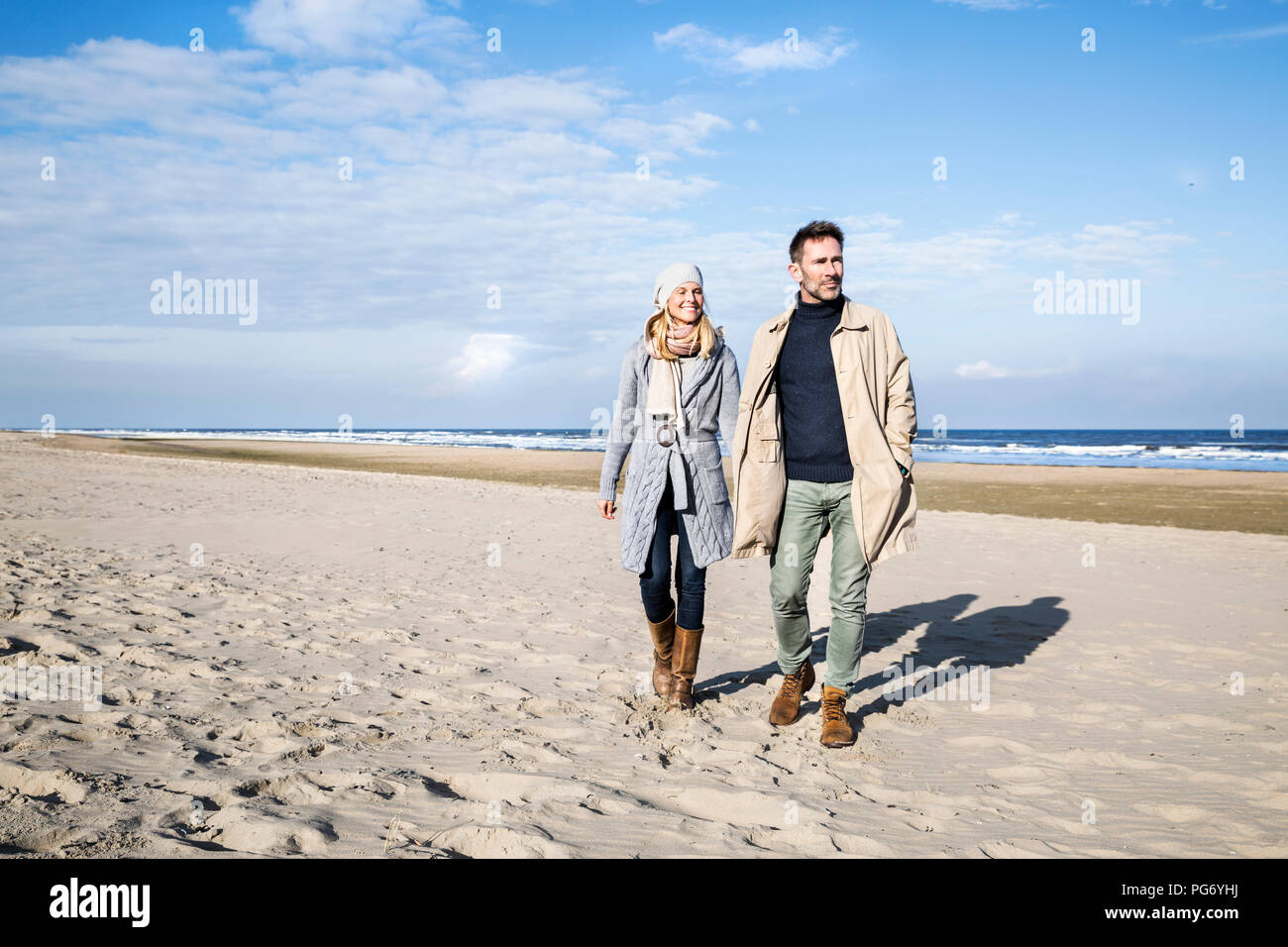 Couple in warm clothing walking on the beach Stock Photo