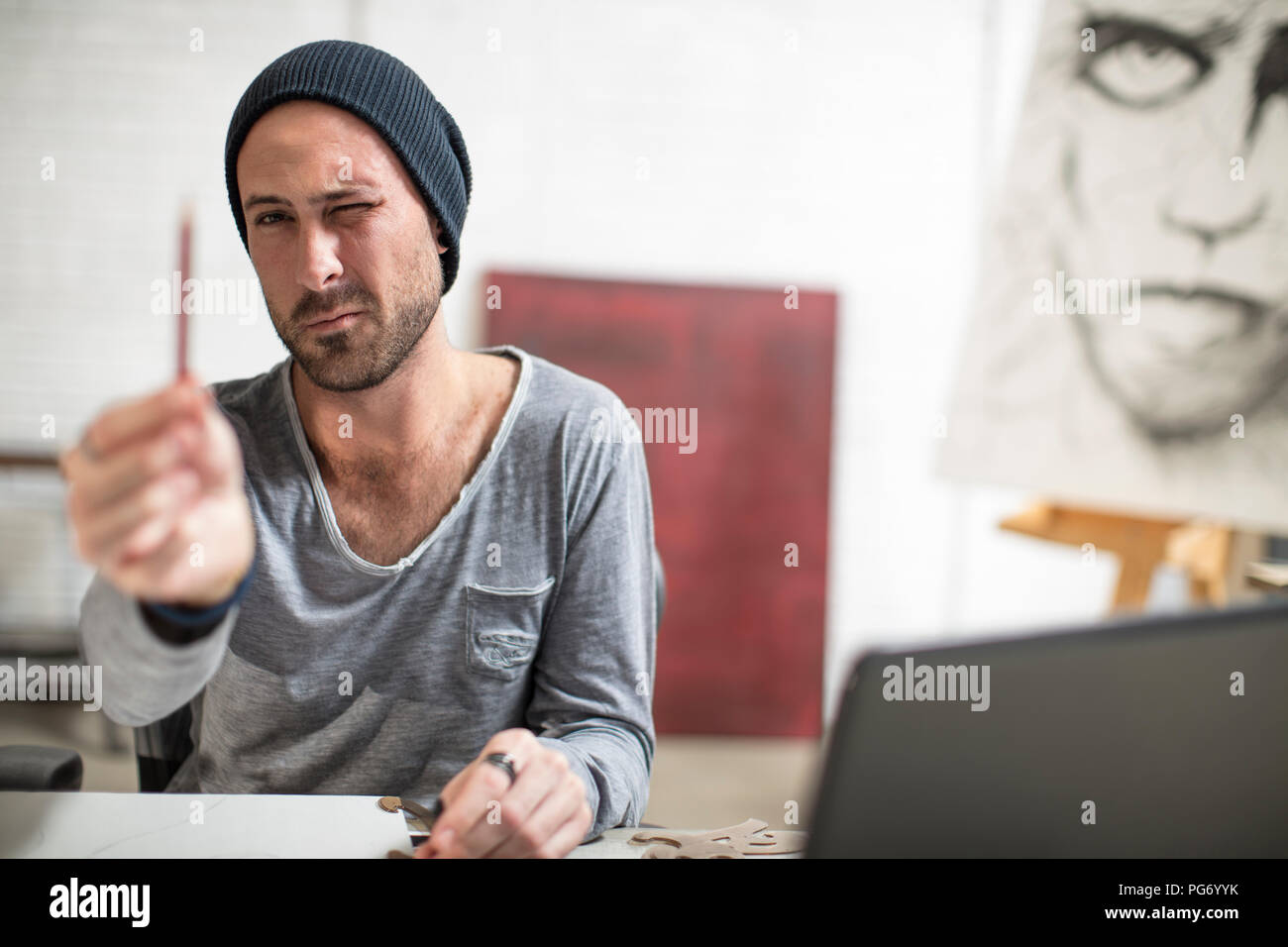 Artist sitting at his desk in studio checking pencil Stock Photo
