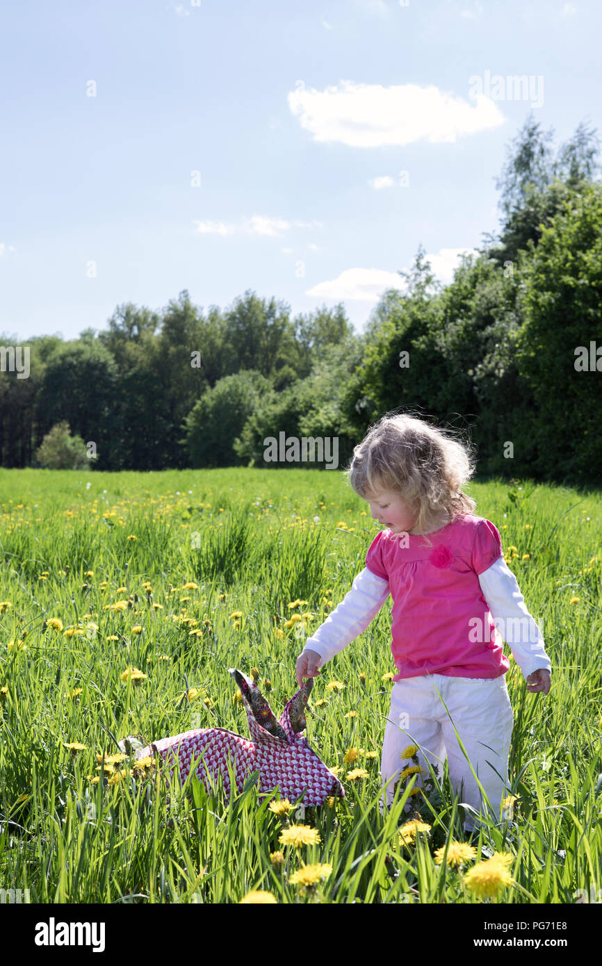 Little girl with origami rabbit on meadow Stock Photo