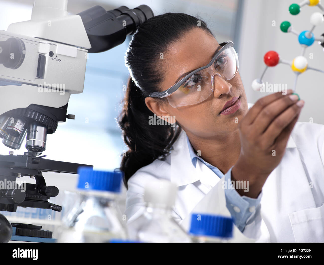 Biotechnology Research, female scientist examining a chemical formula using a ball and stick molecular model in the laboratory Stock Photo