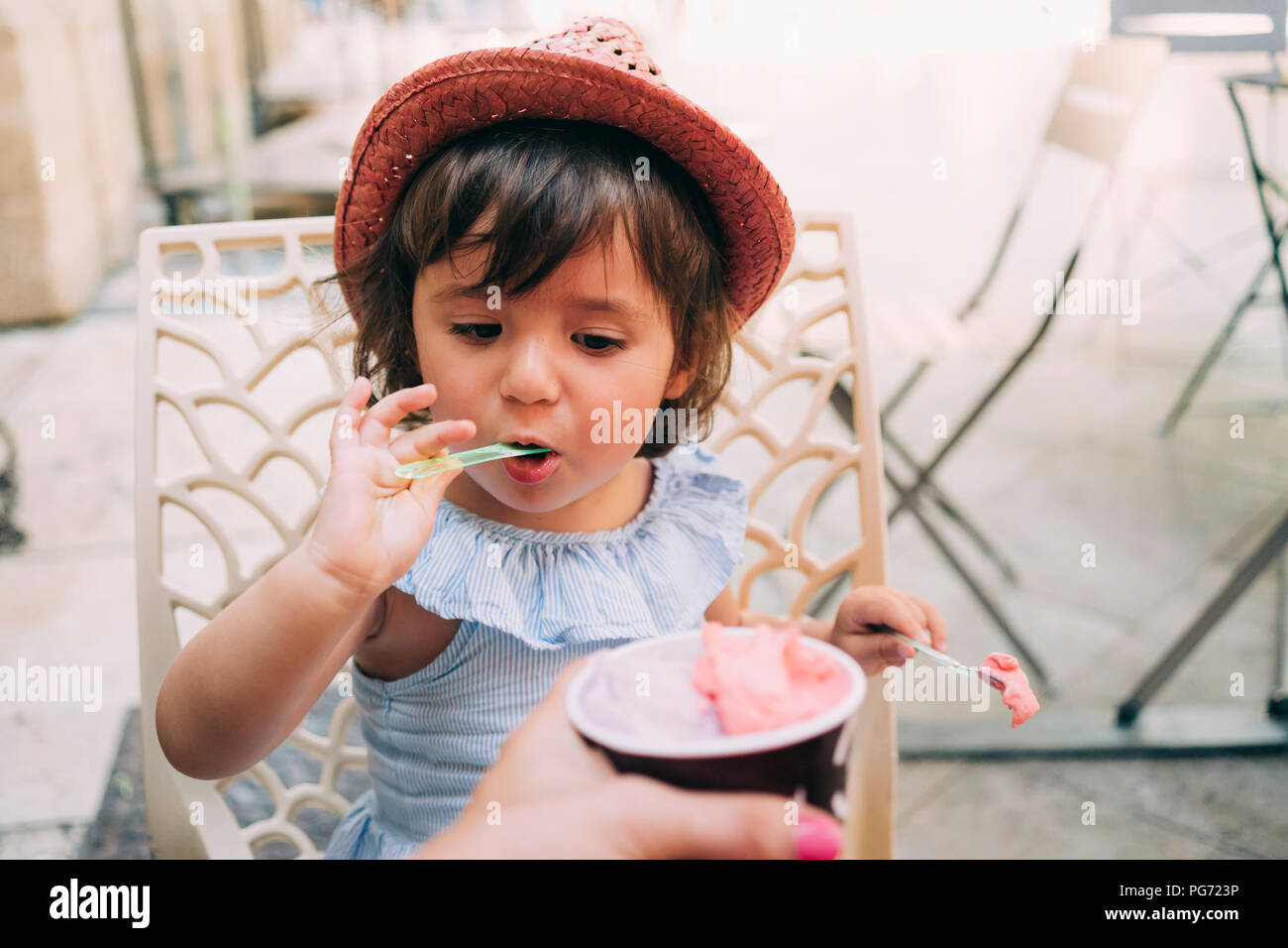 Cute toddler girl eating an ice cream held by her mother Stock Photo