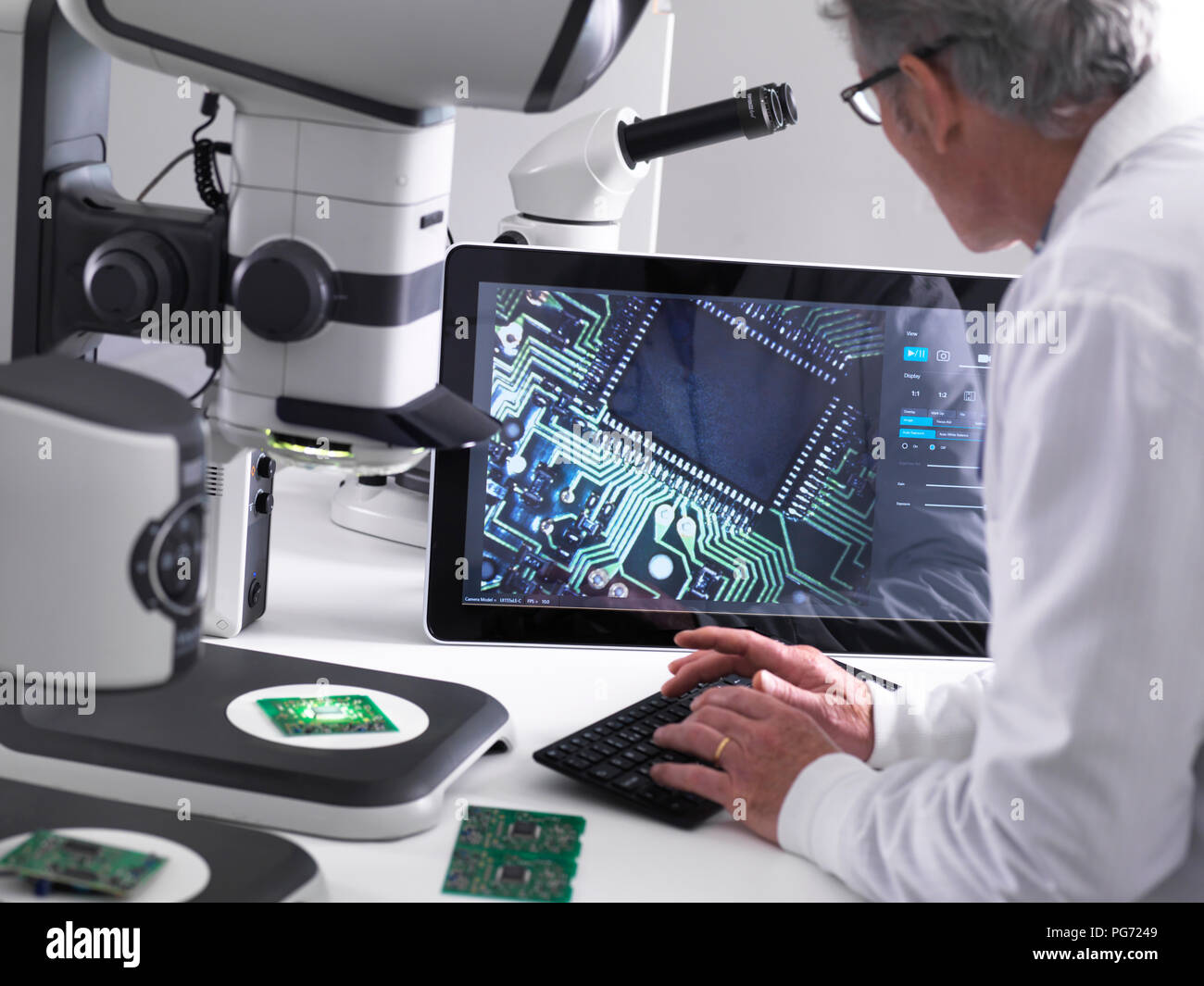 Engineer using a 3d stereo microscope for quality control in the manufacturing of circuit boards for the electronics industry Stock Photo