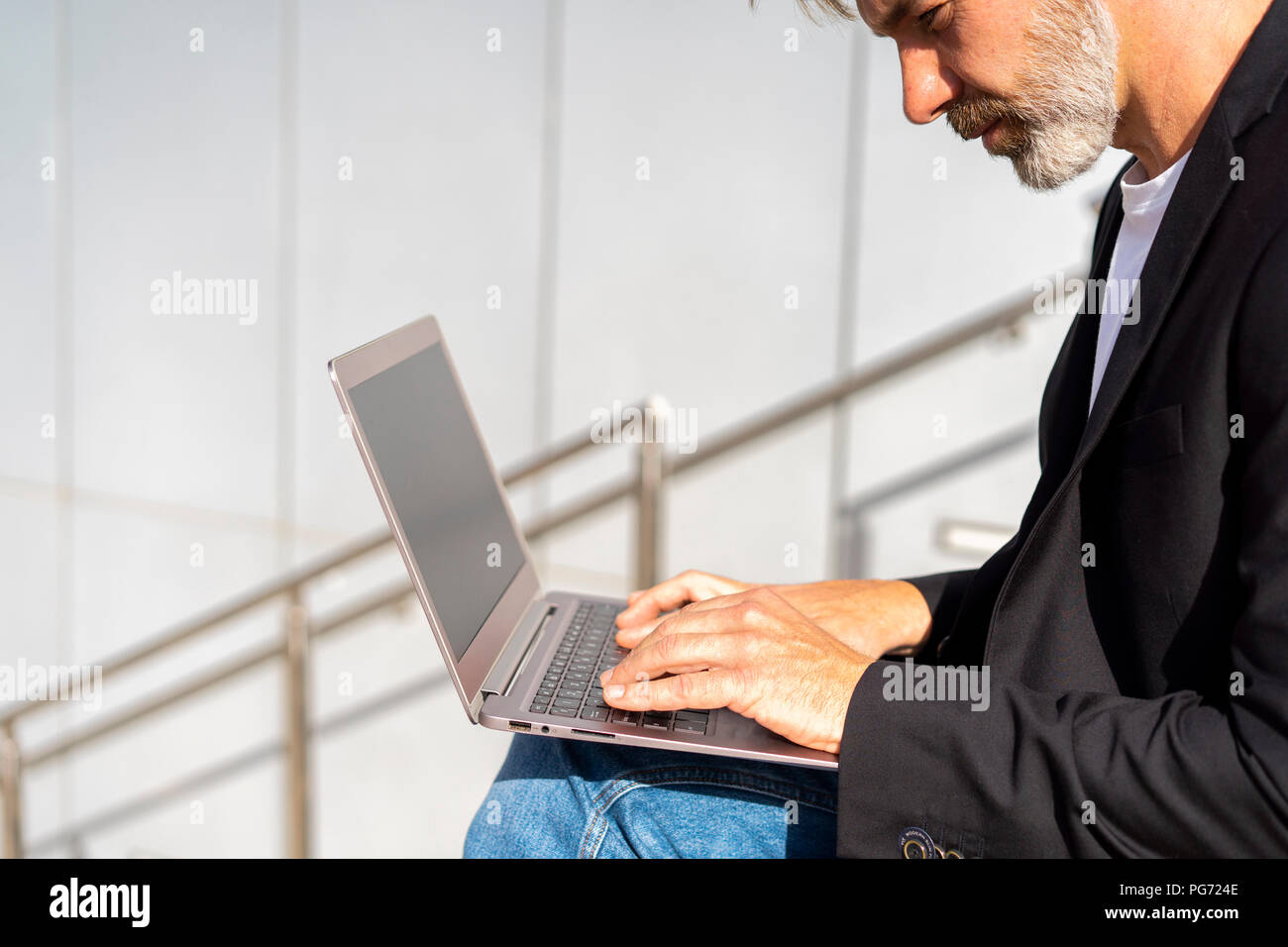 Businessman sitting outdoors using laptop Stock Photo