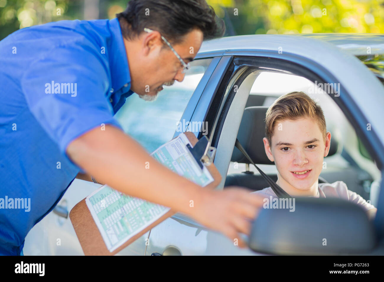 Learner driver with instructor checking wing mirror of a car Stock Photo