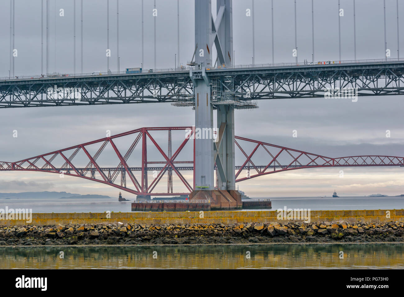 FORTH RAILWAY BRIDGE OVER THE FIRTH OF FORTH SCOTLAND AND THE OLD ROAD BRIDGE UNDERGOING REPAIR Stock Photo