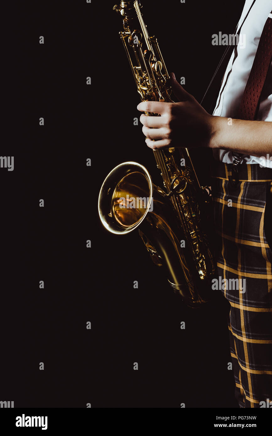 cropped shot of stylish young musician holding saxophone isolated on black Stock Photo