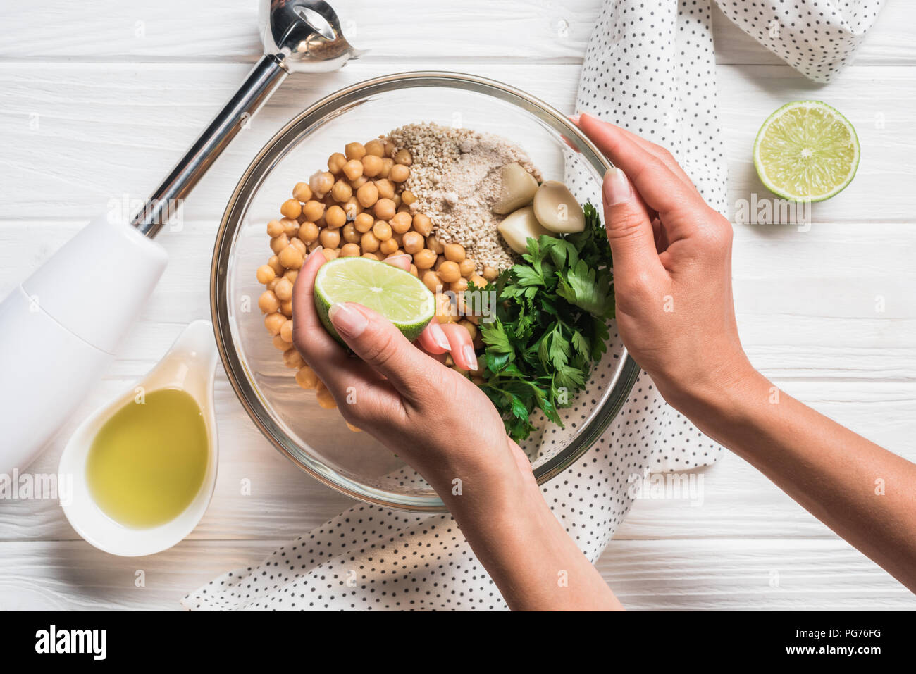 Cropped shot of woman, ingredients for hummus in bowl, olive oil and blender  on wooden tabletop Stock Photo - Alamy