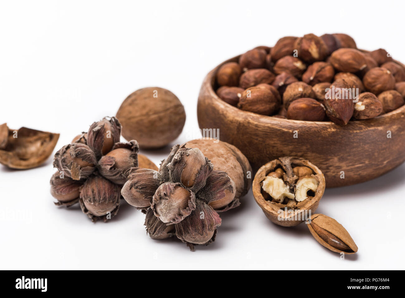 hazelnuts in wooden bowl near walnuts and almond isolated on white background Stock Photo