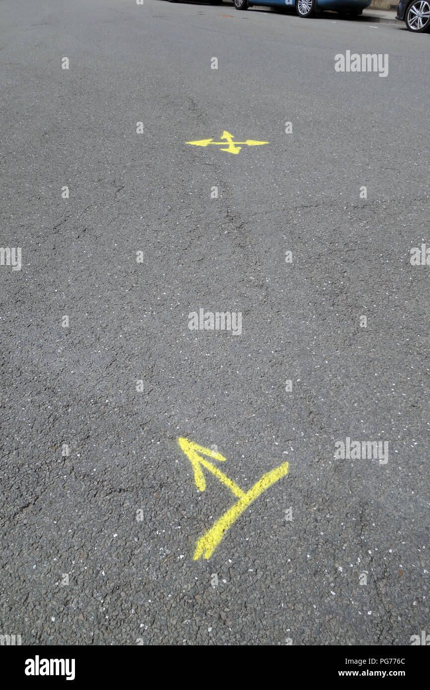 Yellow painted arrows painted on tarmac road surface Stock Photo Alamy