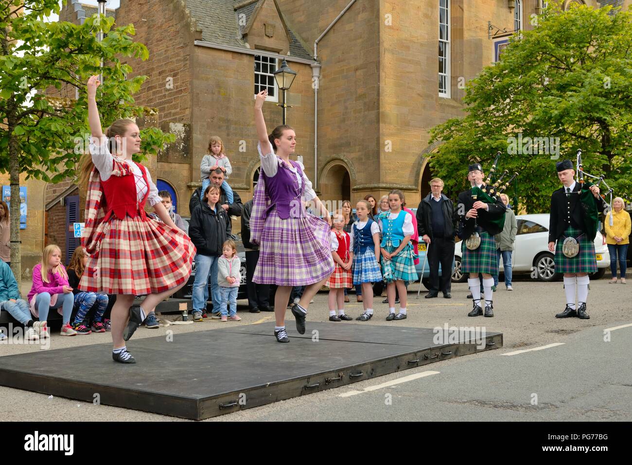 Young Scottish Highland dancers performing for tourist in the main square in Dornoch, Sutherland, Scotland, UK Stock Photo