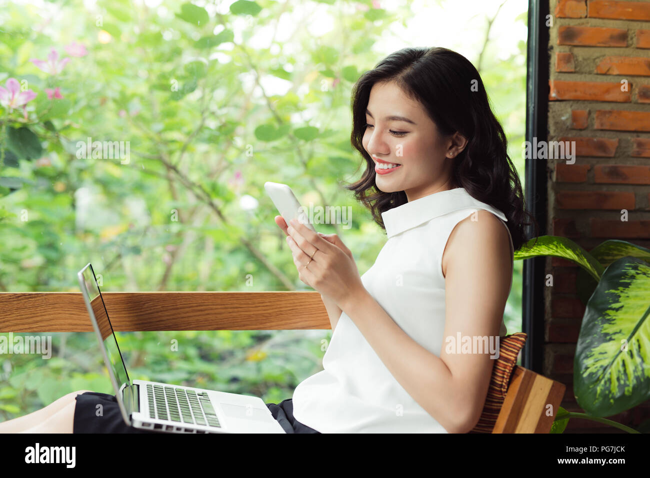Confident young asian woman in smart casual wear typing on phone. Stock Photo