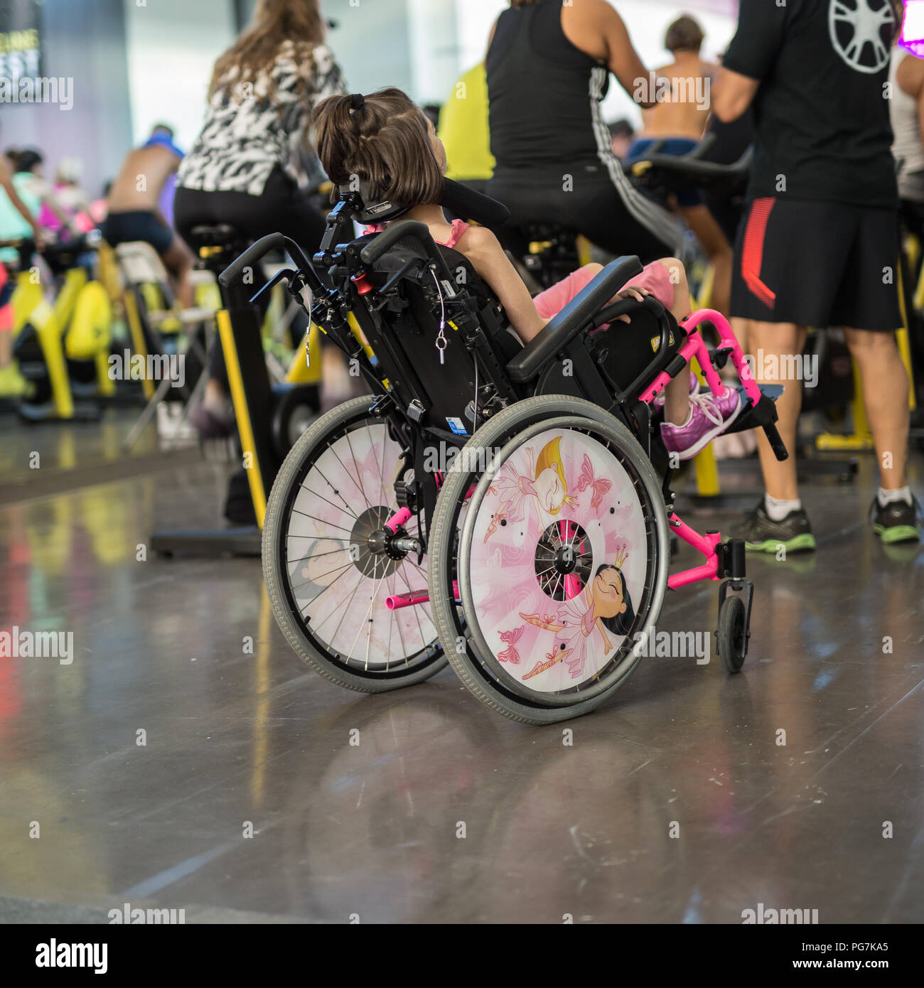 Girl in Pink Wheelchair attending a Fitness Workout with Spinning Bike  Stock Photo - Alamy