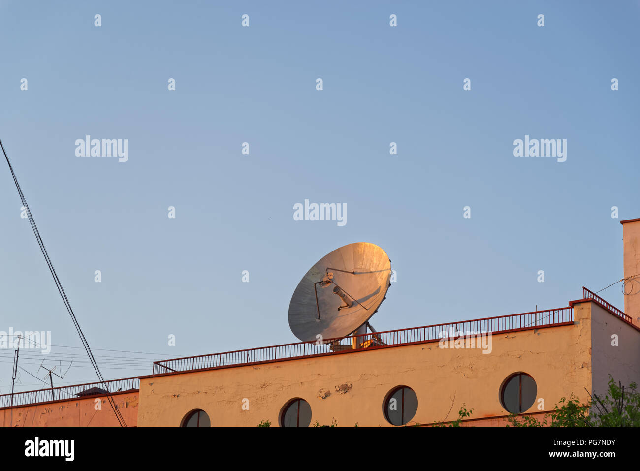 Big communication satellite dish on the roof of old building against clear blue sky. Khabarovsk, Russia Stock Photo