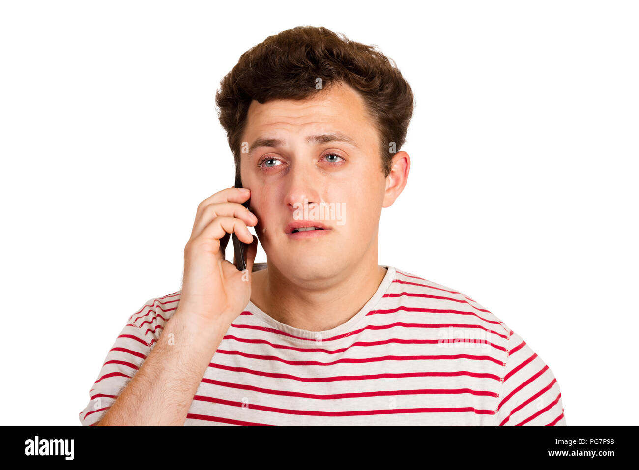 Young man crying over the bad news he is receiving on his phone. emotional man isolated on white background. Stock Photo