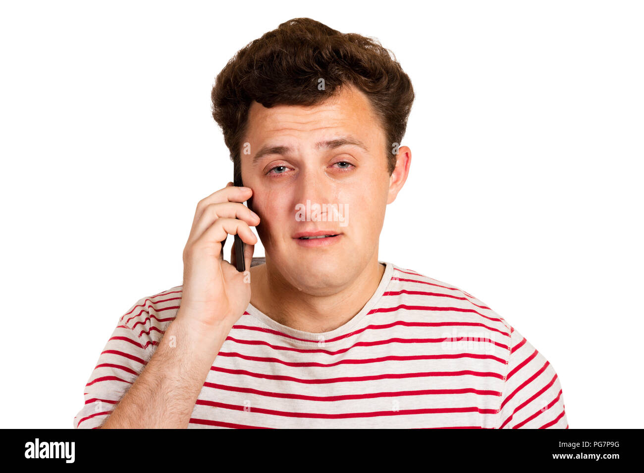 A young man heard the bad news on the phone and begins to cry. emotional man isolated on white background. Stock Photo
