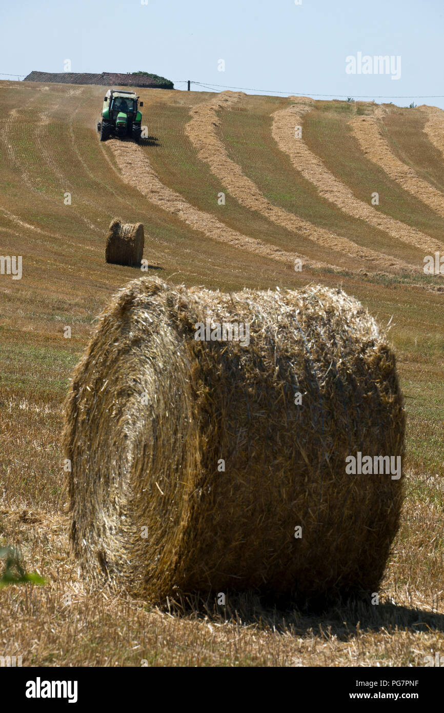 A tractor and baling machine xollecting and baiing hay near Najac, Aveyron, Occitanie, France, Europe Stock Photo