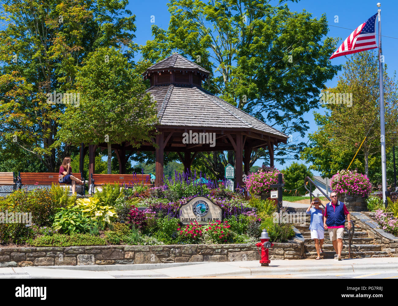 BLOWING ROCK, NC, USA,-23 AUG 2018: City Park, with a gazebo, flag pole, a couple walking. and woman using cell phone. Stock Photo