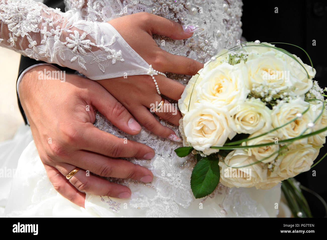 Bride and groom hands with wedding rings and bouquet of roses Stock Bride and groom hands with wedding rings and bouquet of roses Stock