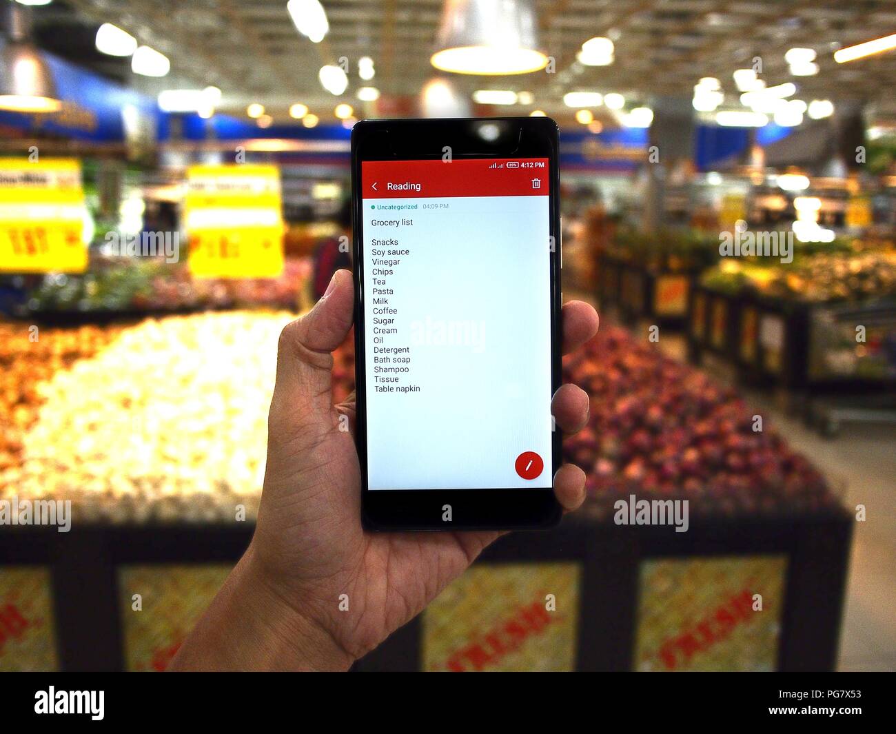 stock photo of a hand holding a smartphone with grocery list while