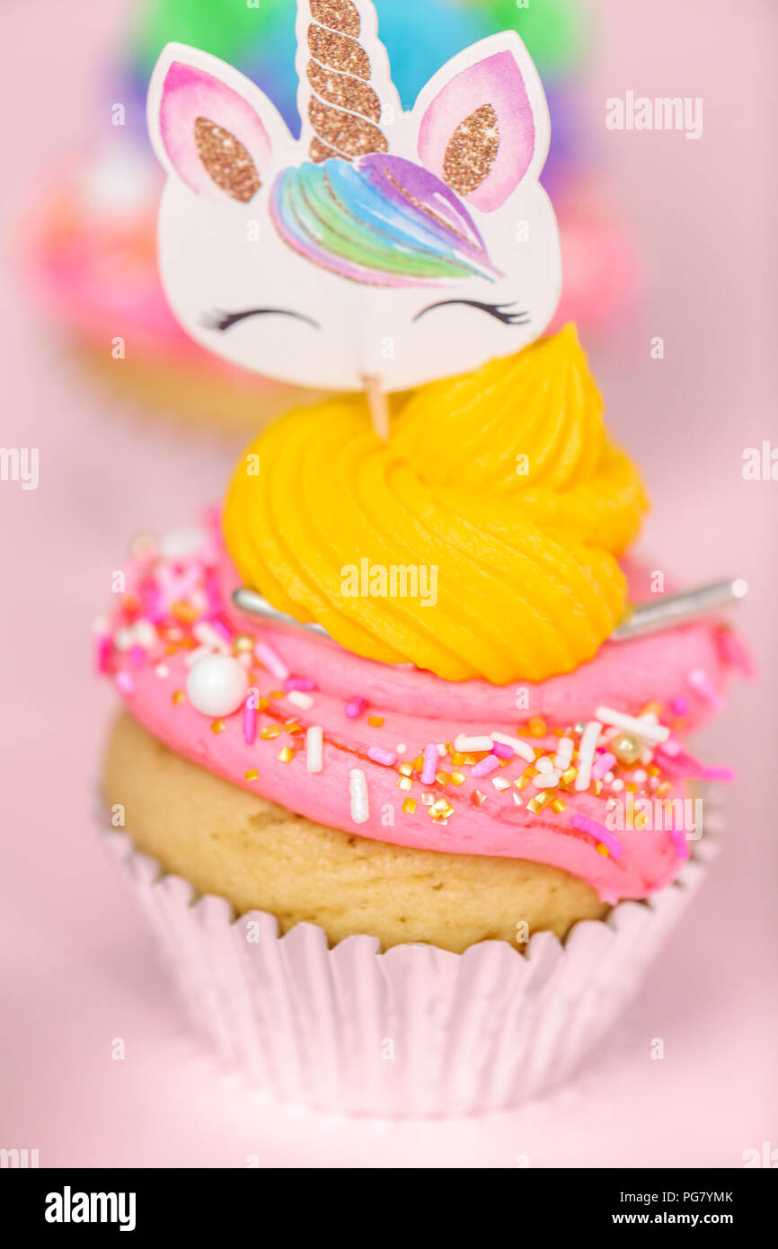 Fancy unicorn cupcakes with multicolor buttercream icing and unicorn cupcake topper on pink