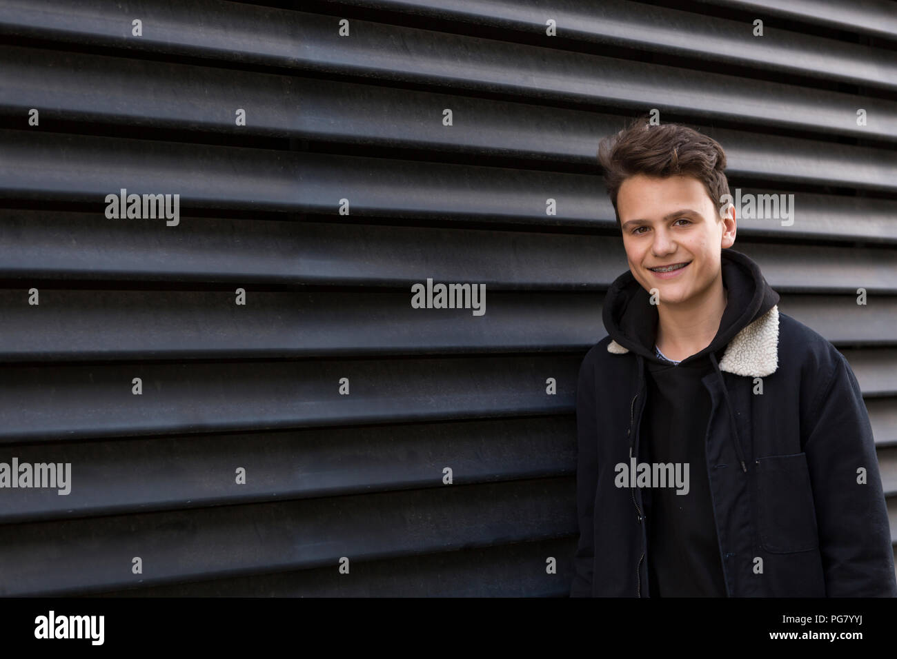 Portrait of smiling teenage boy against black background Stock Photo