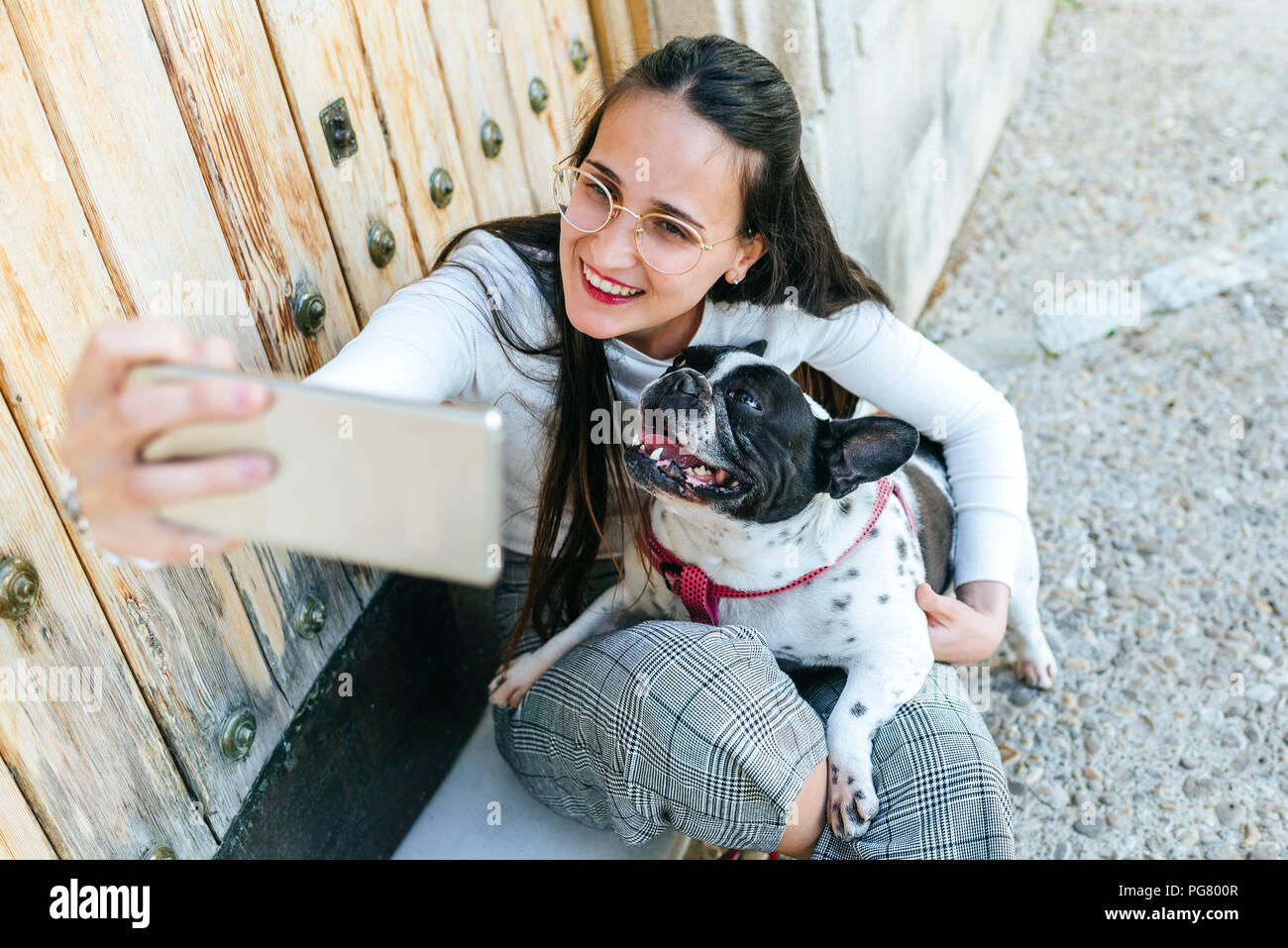 Young woman using smartphone, taking a selfie with her dog Stock Photo