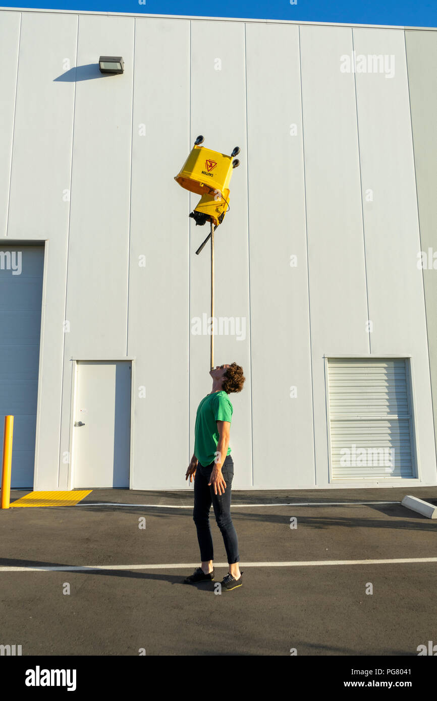 Acrobat balancing bucket on mop on his chin Stock Photo