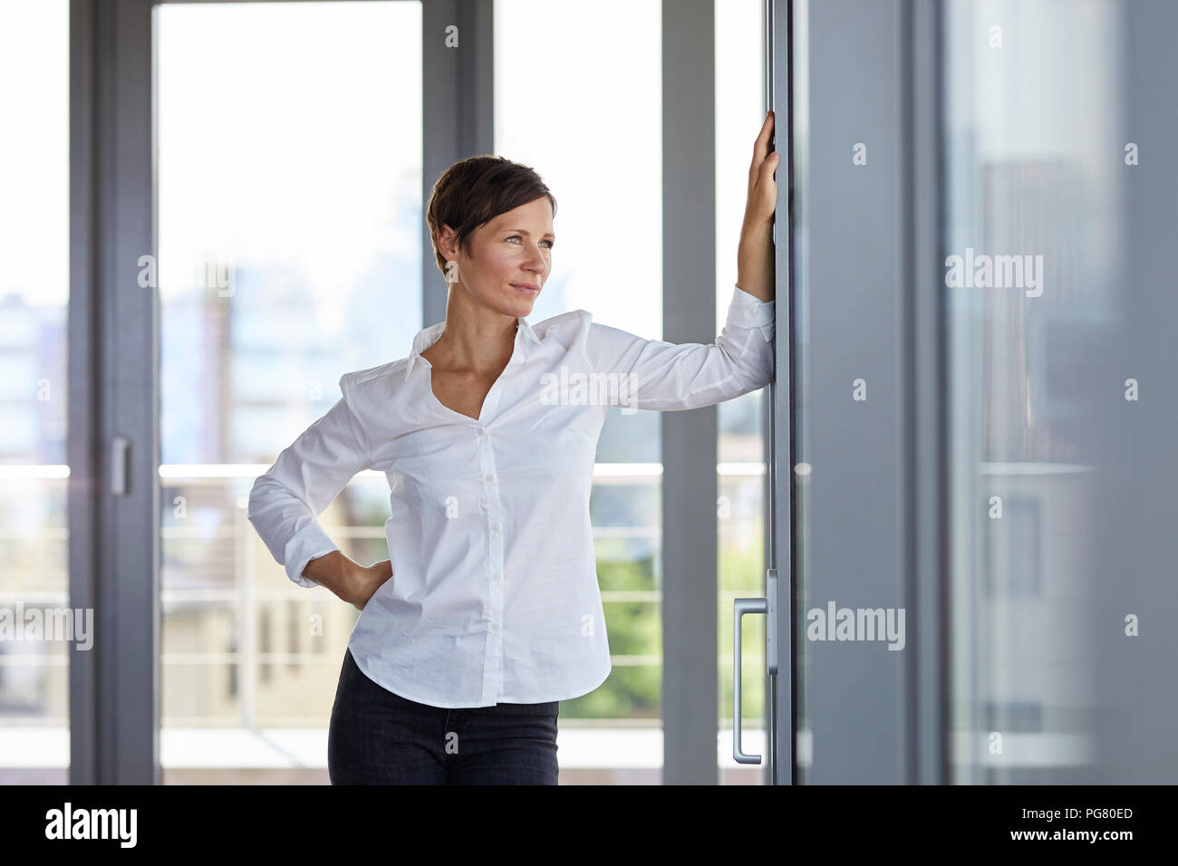Businesswoman standing in office looking out of window Stock Photo