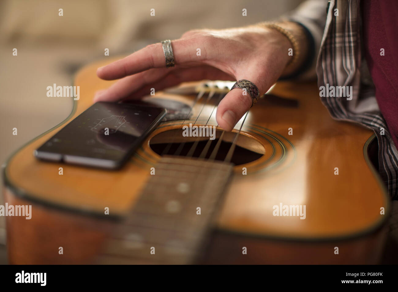 Close-up of man's hand, cell phone and guitar Stock Photo
