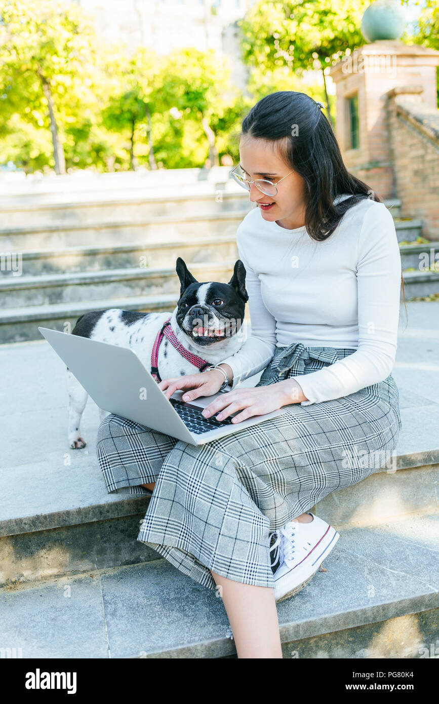 Woman using laptop next to her dog, sitting on stairs Stock Photo