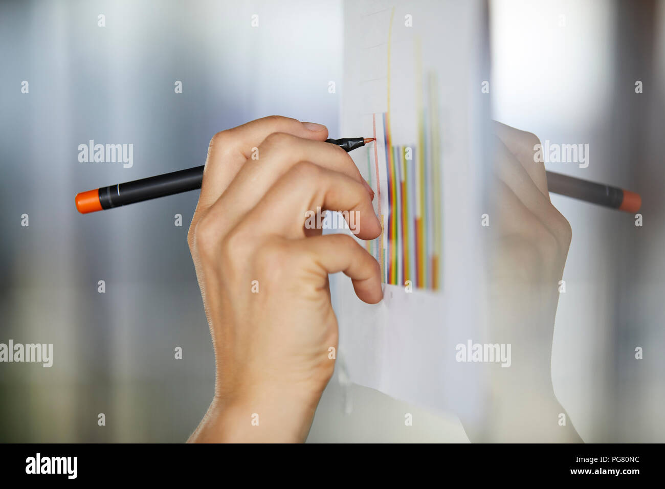 Hand drawing bar charts on paper at glass pane Stock Photo