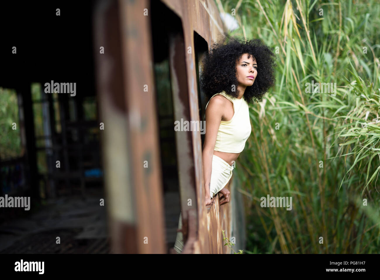 Portrait of fashionable young woman leaning out of abandoned and destroyed old train Stock Photo