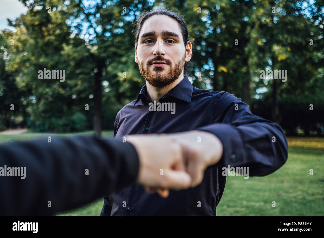 Young businessman greeting business partner in a park, negotiating business transactions Stock Photo