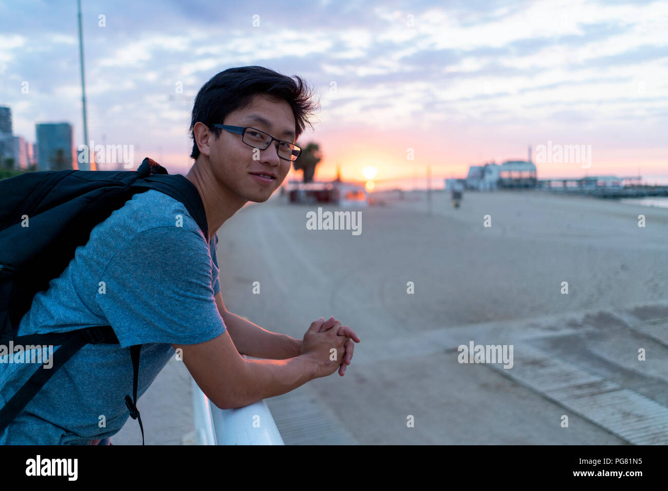 Young Chinese man with backpack looking at beach Stock Photo