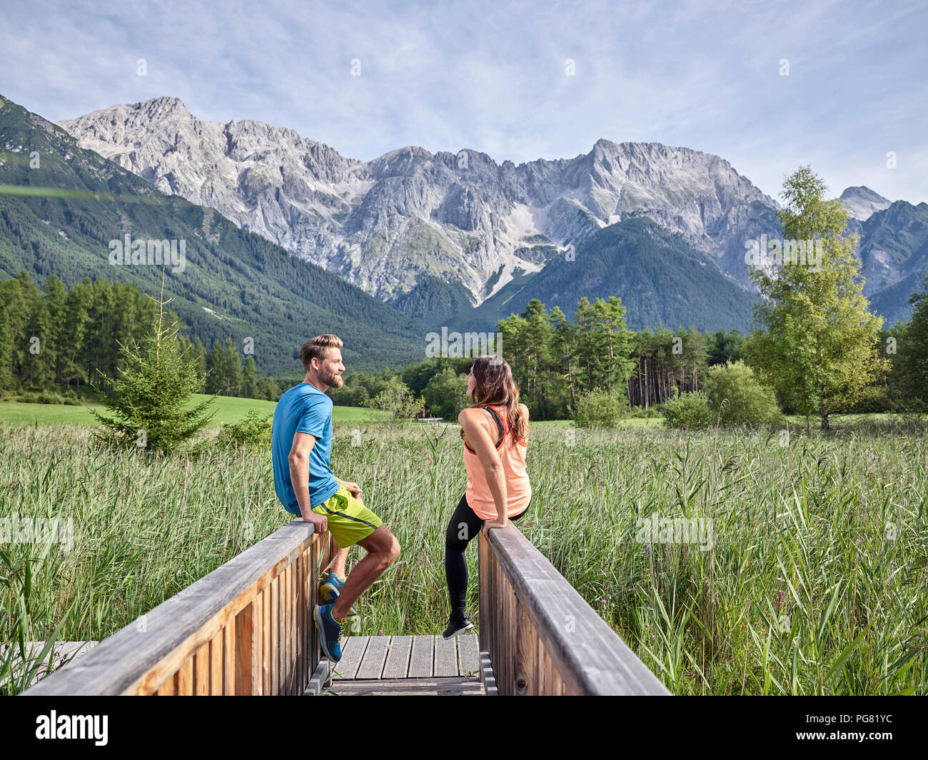 Austria, Tyrol, Mieming, couple resting on a boardwalk in the mountains Stock Photo