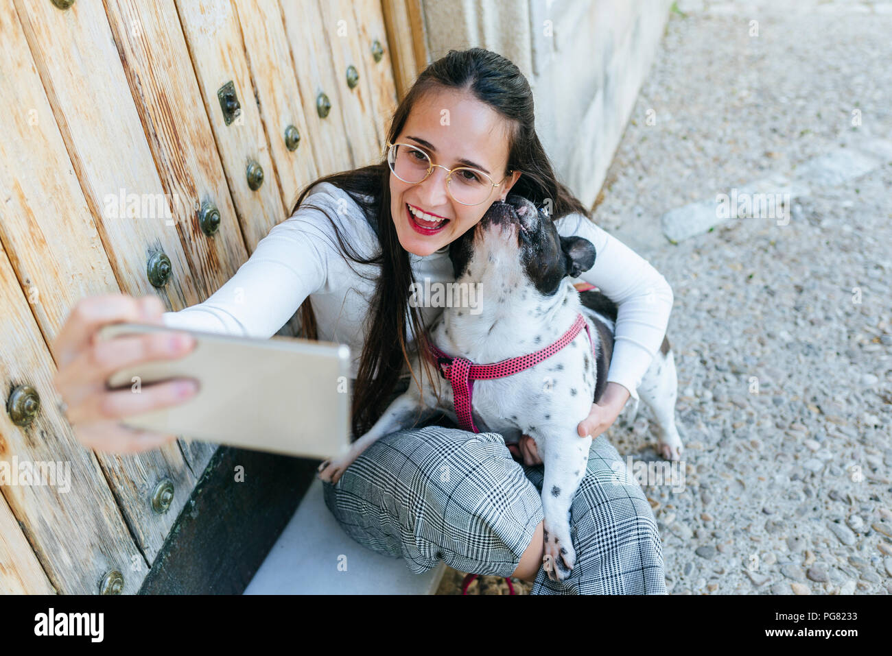 Young woman using smartphone, taking a selfie with her dog Stock Photo