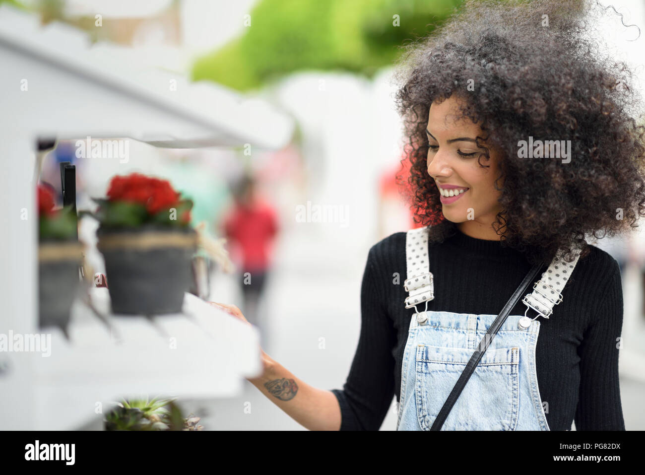 Smiling young woman watching potted plants of a flower shop Stock Photo