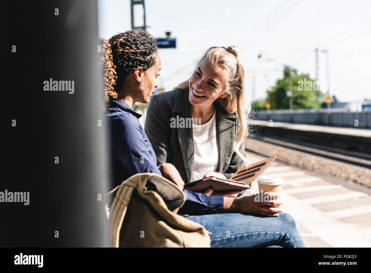 Friends waiting at train station using digital tablet Stock Photo