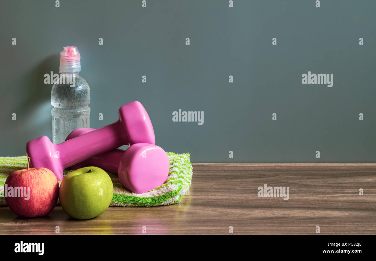 Healthy and active lifestyle background concept. Green and Red Apples, Dumbbells and bottle of water on wood floor with copy space. Stock Photo