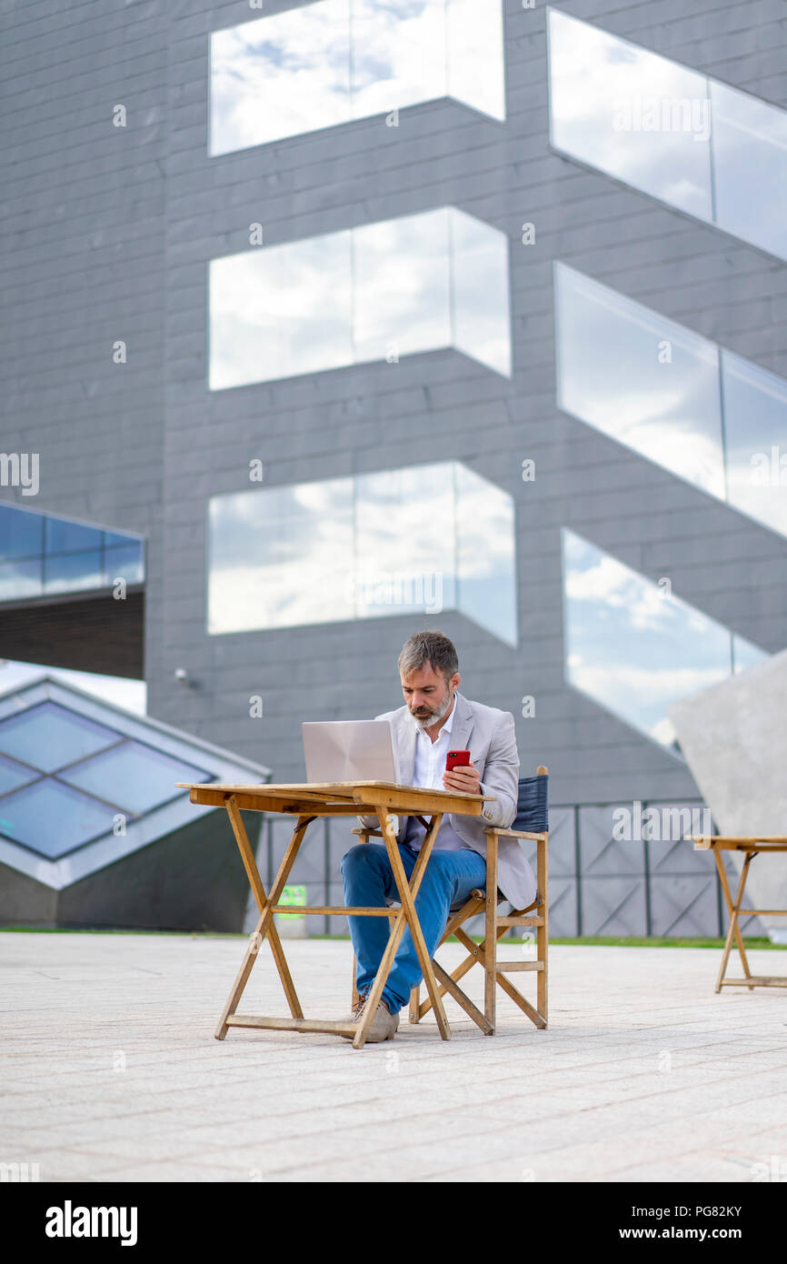 Spain, Barcelona, businessman working on laptop outdoors Stock Photo