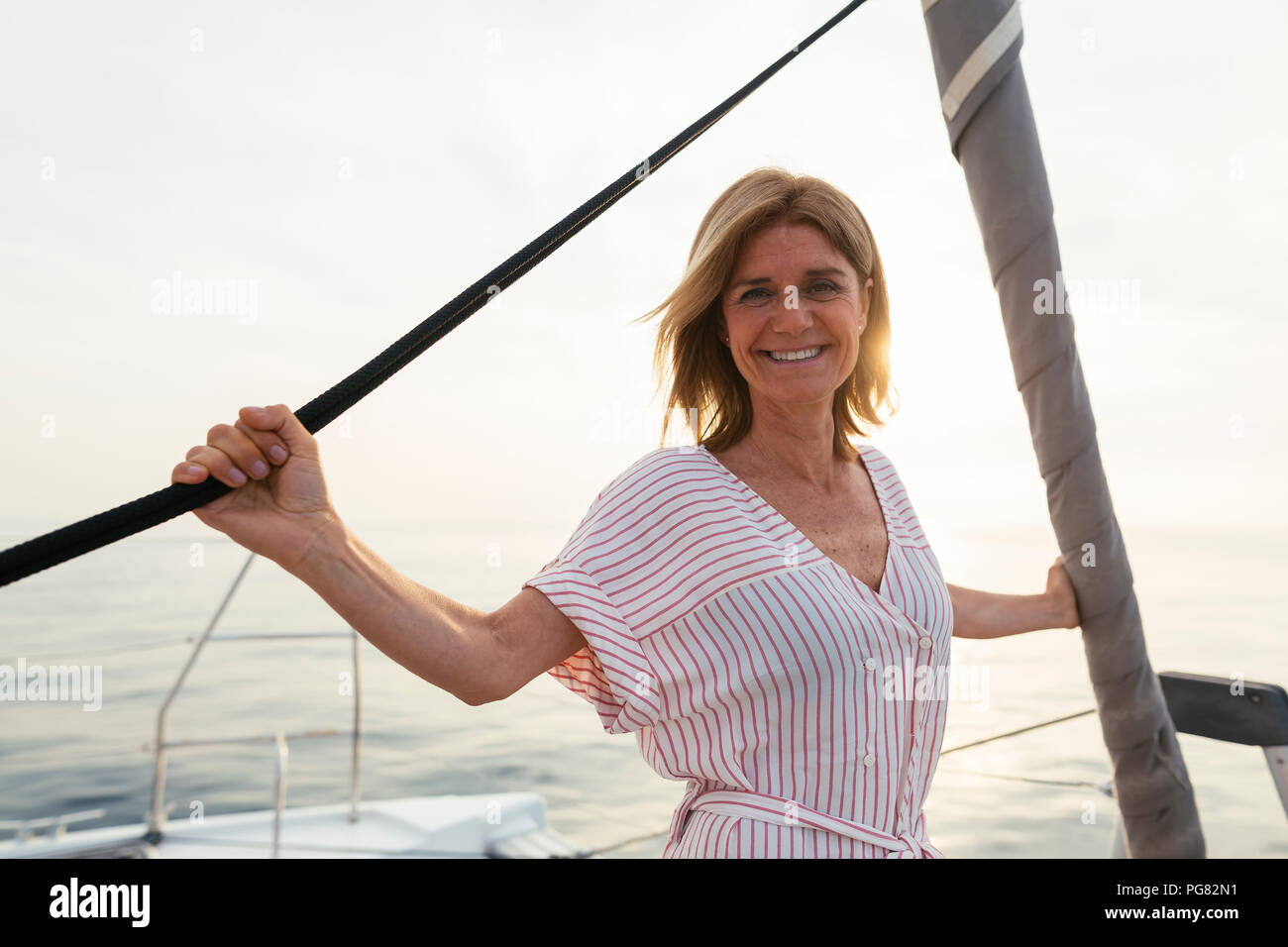 Mature woman on catamaran, watching sunset Stock Photo