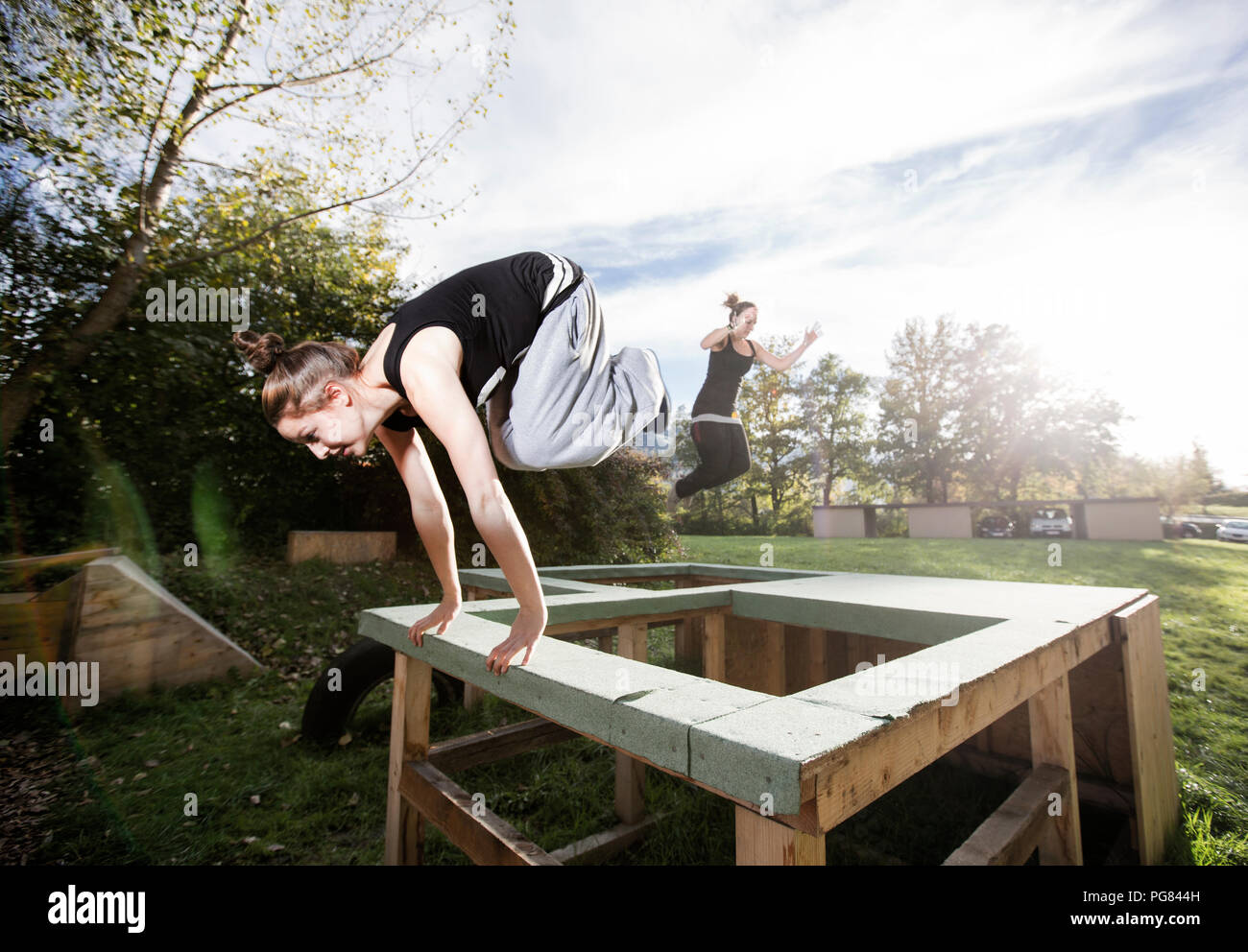 Woman jumping over barrier during freerunning exercise Stock Photo