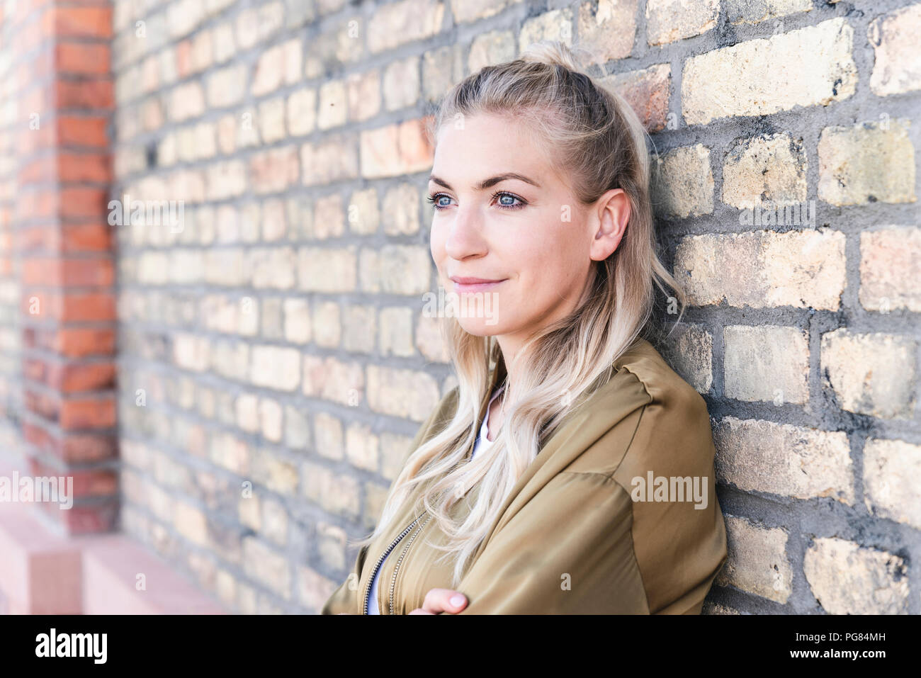 Portrait of a beautiful young woman in front of brickwall Stock Photo