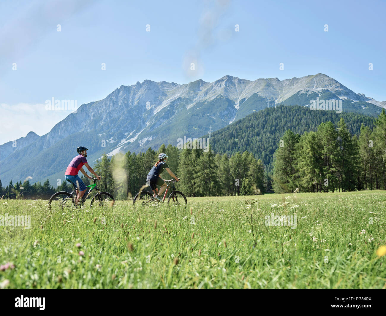 Austria, Tyrol, Mieming, couple riding bike in alpine scenery Stock Photo