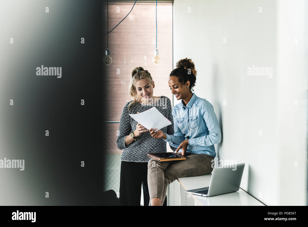 Young women working together in office, reading documents Stock Photo