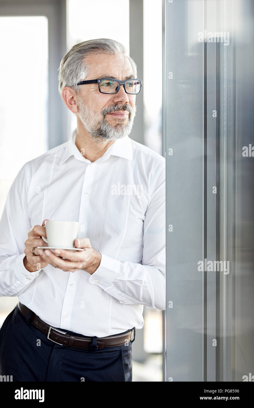 Businessman with cup of coffee looking out of window Stock Photo