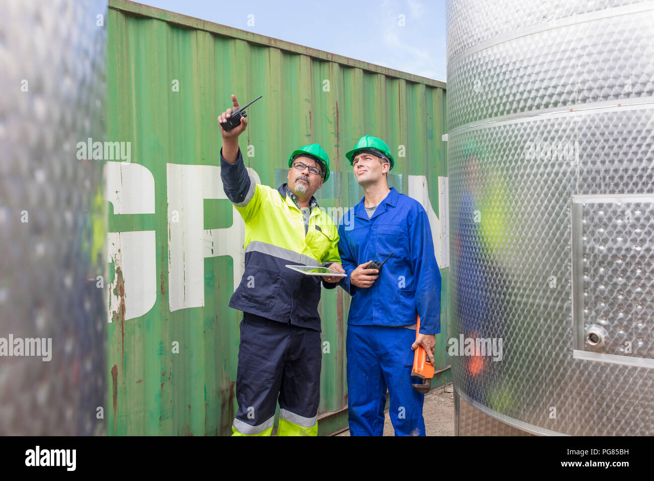 Worker with tablet at container talking to co-worker Stock Photo