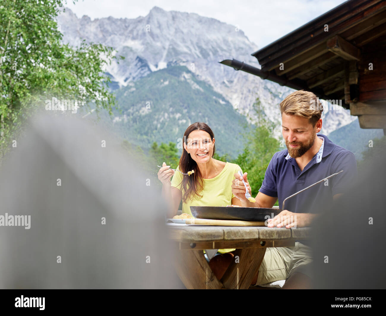 Happy couple having a snack at a hut in the mountains Stock Photo