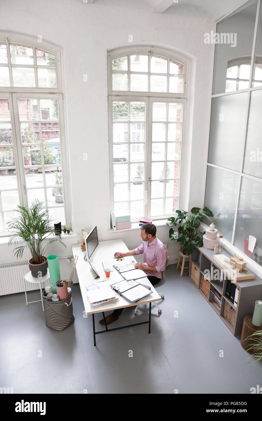 Man working at desk in a loft office Stock Photo